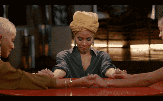 Jada bowing her head and holding hands with her mother and daughter.