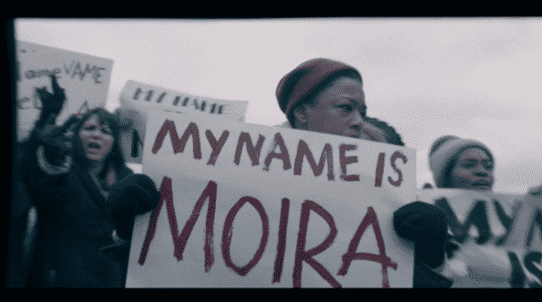 Moira holding a sign which says, "My name is Moira"