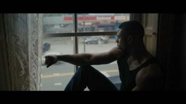 Adonis (Michael B. Jordan) sitting in a window.