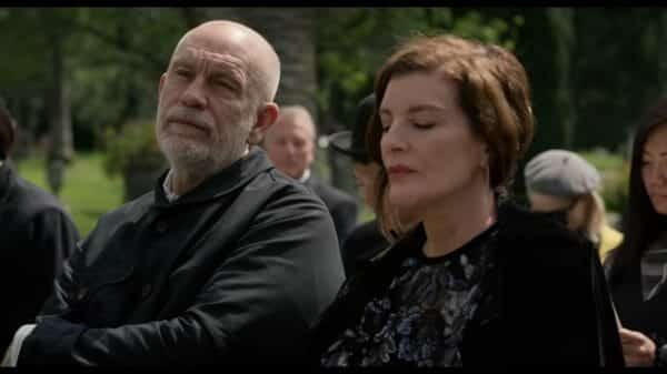 Piers (John Malkovich) and Rhodora (Rene Russo) at a funeral together.