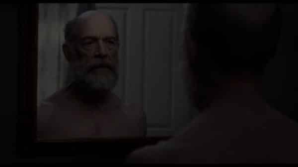 Steve - 60 (J.K. Simmons) looking into a mirror.