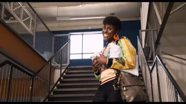 April (Issa Rae) smiling while walking up stairs.