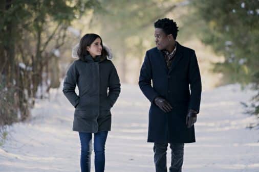 Isabela Moner and Shameik Moore walking in the snow together.