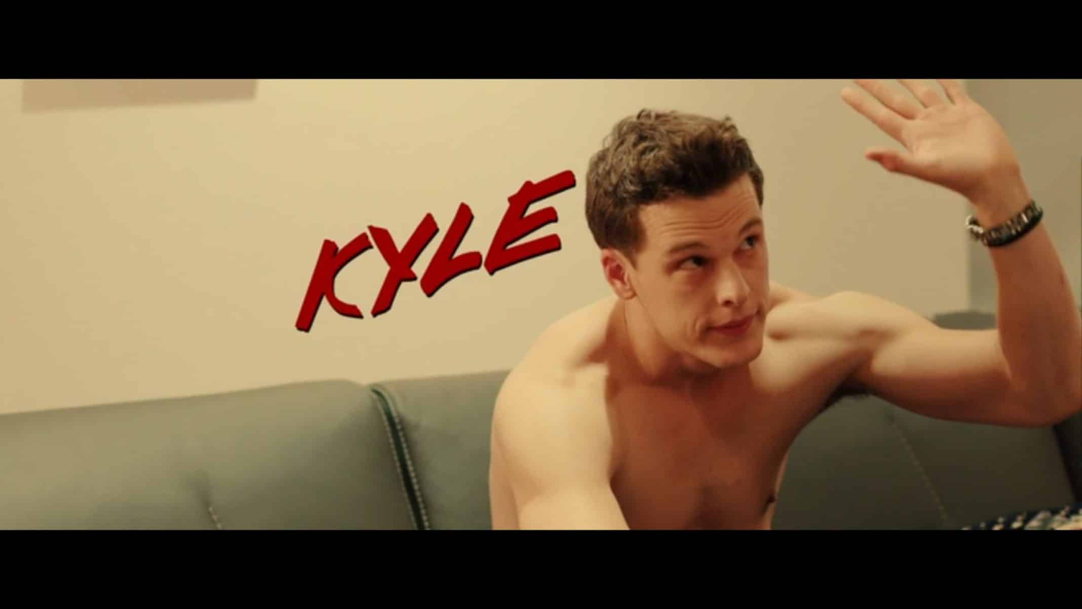 Kyle (Grant Harvey) sitting on a couch, with his shirt off.