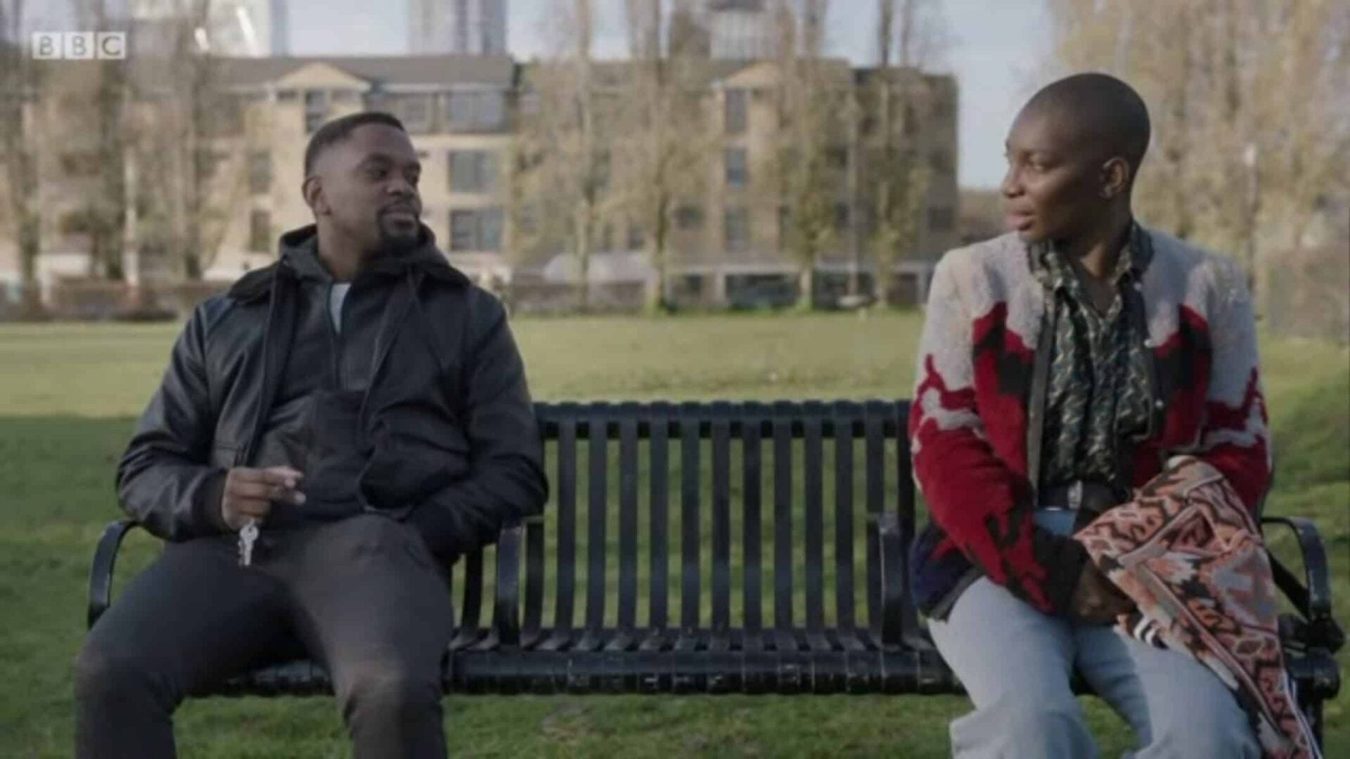 Simon (Aml Ameen) and Arabella (Michaela Coel) talking on a bench.