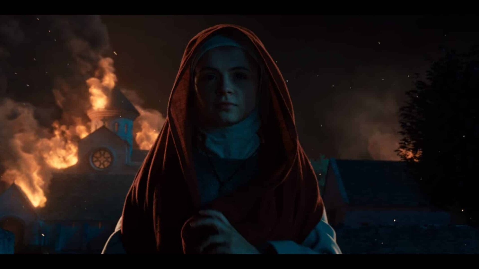 Sister Iris (Emily Coates) walking from a fire she caused.