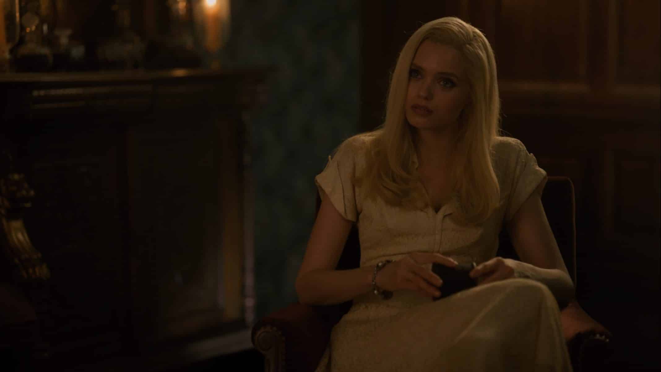 Christina (Abbey Lee) sitting in a chair, watching Atticus.