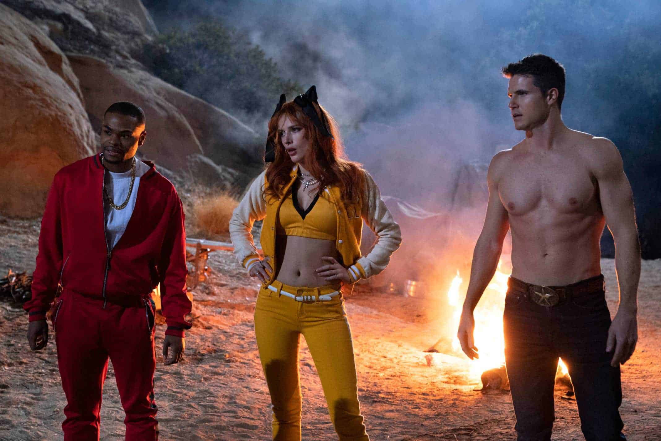 ANDREW BACHELOR as JOHN, BELLA THORNE as ALLISON and ROBBIE AMELL as MAX standing in front of a fire.