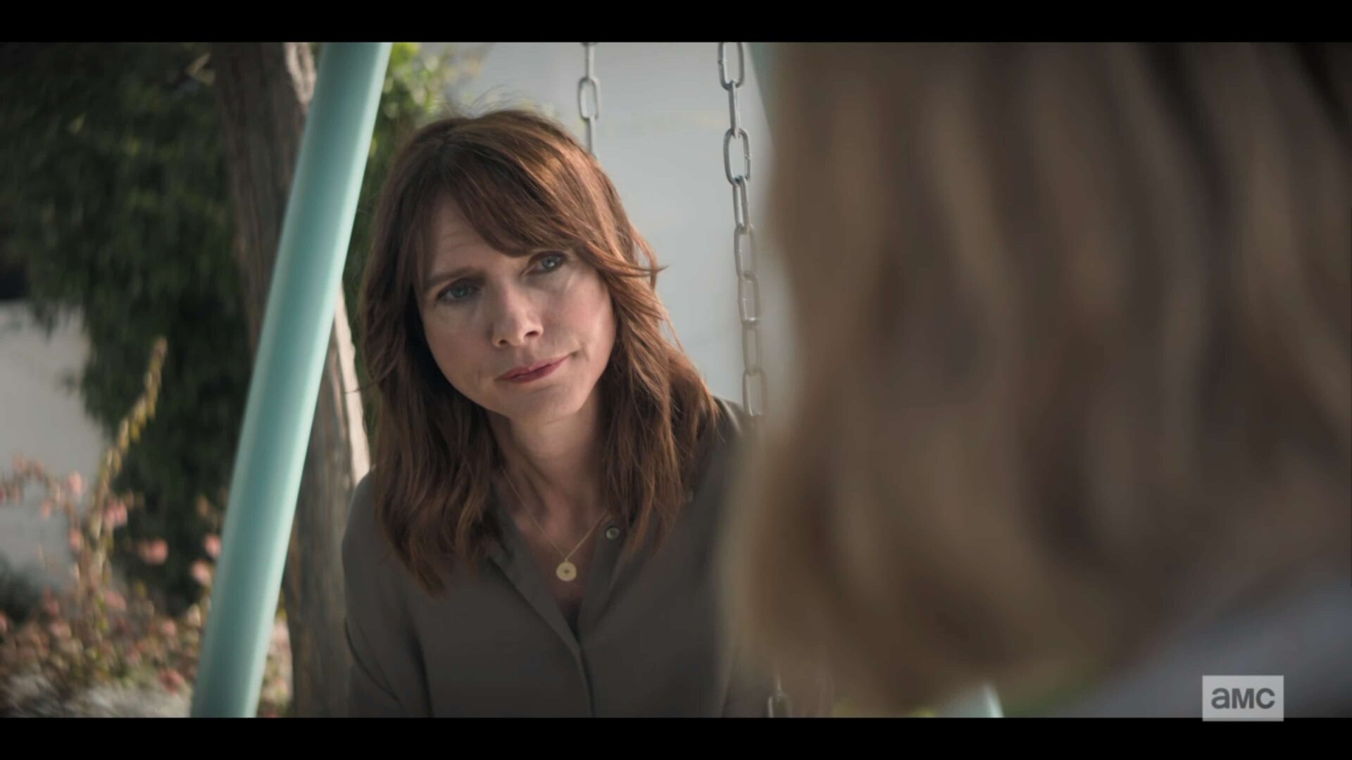 Jennifer (Dolly Wells) sitting on a swing.