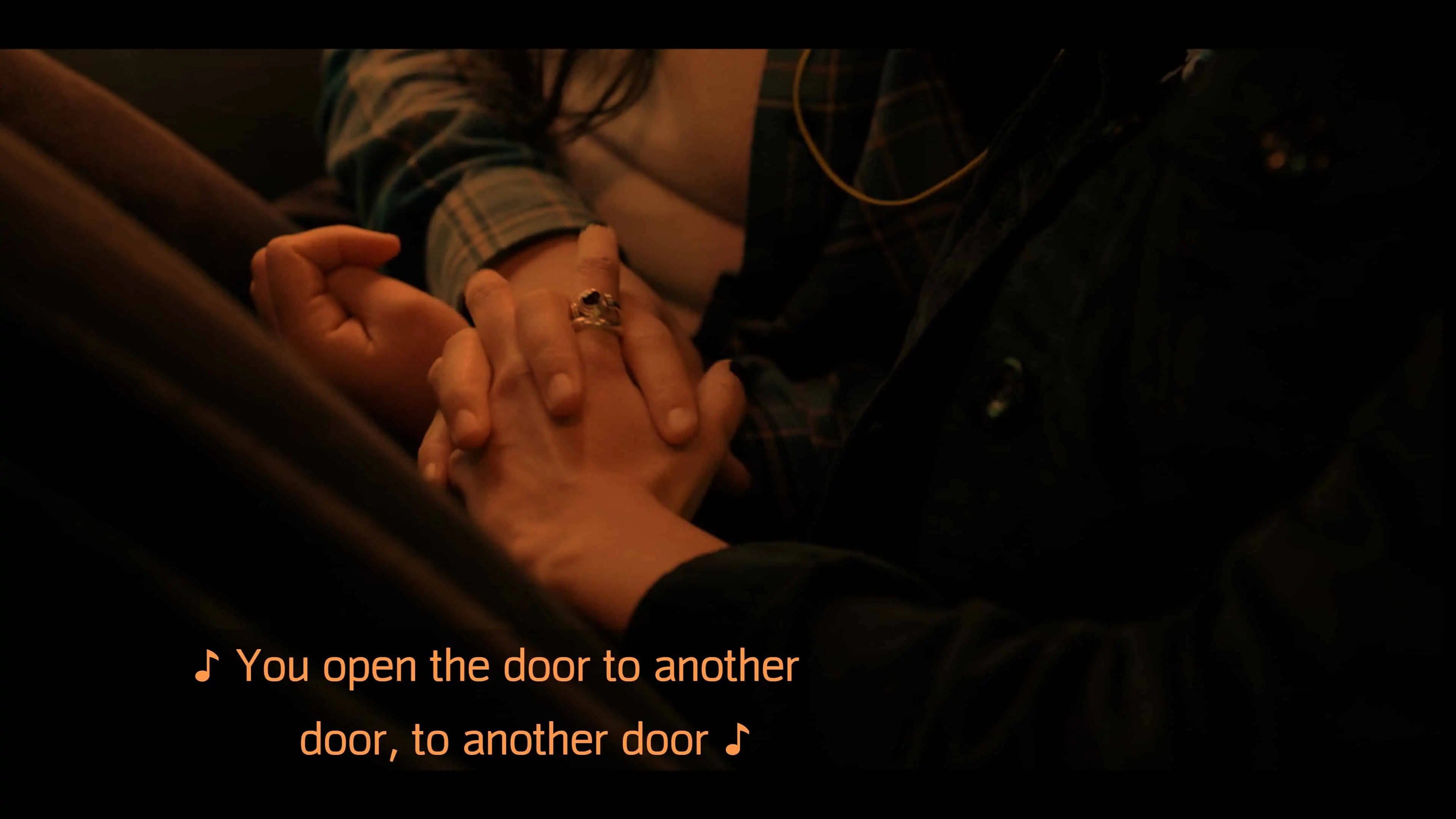 Greta and Riley intertwining fingers as they listen to a song on Riley's phone
