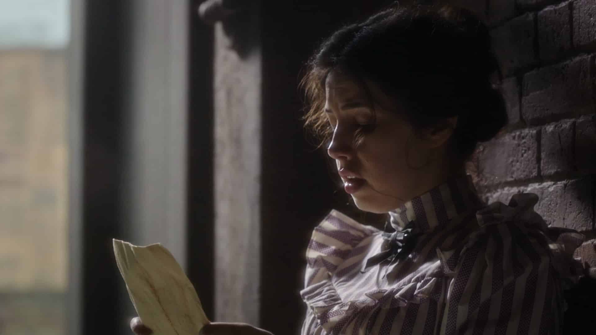 Beth (Ella Smith) reading a poster advertising Amalia's help