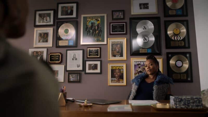 Barb (Erika Alexander) in her office with plaques and covers featuring her