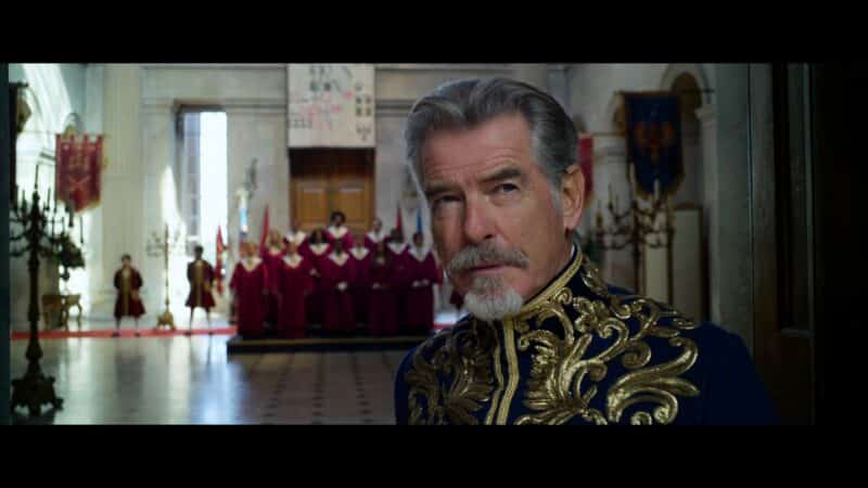 King Rowan (Pierce Brosnan) with a choir behind him