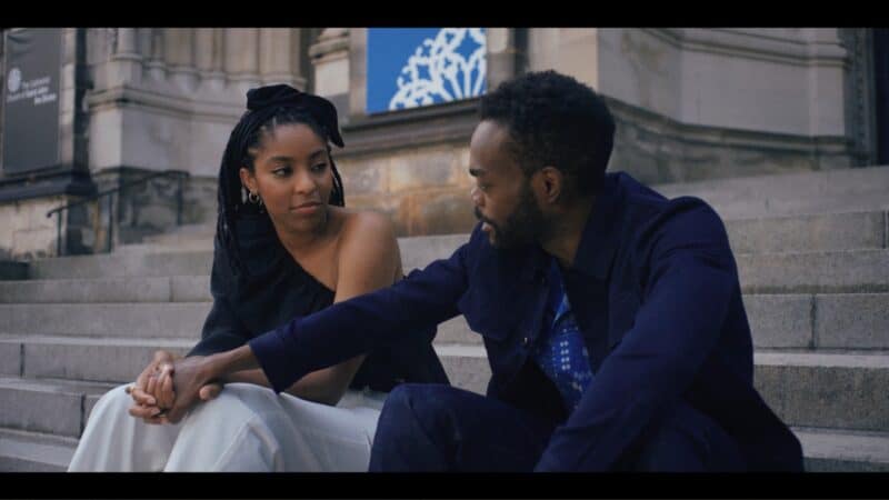 Mia and Marcus chatting on the steps of a church