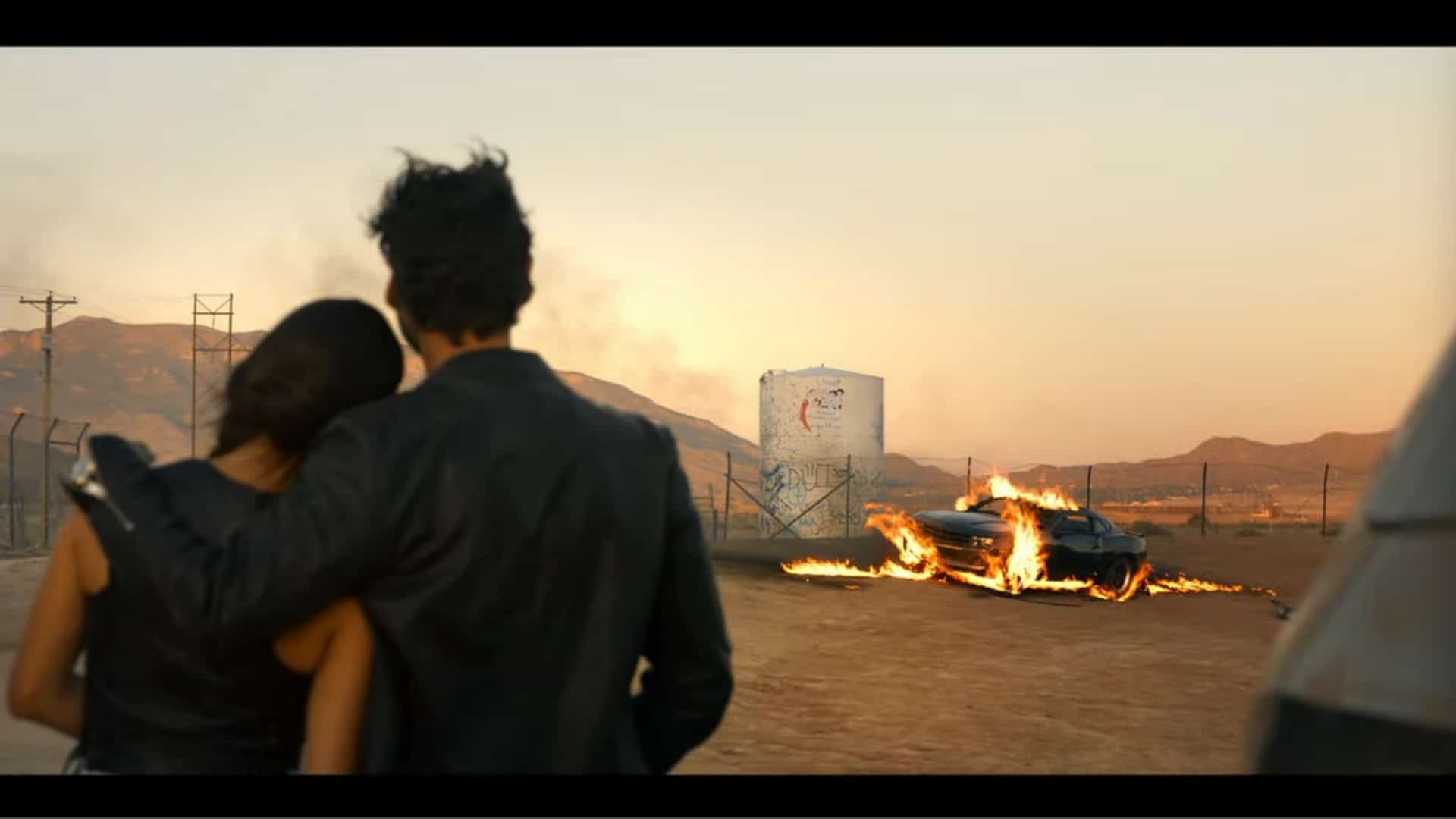 Nadia and Arman watching Carlos' car in flames