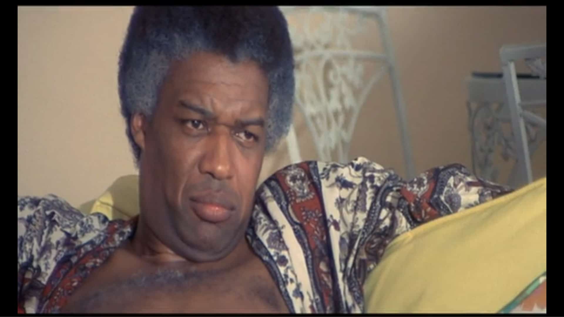 Mr. Peters (Bernie Casey) lounging and having a conversation with his agents