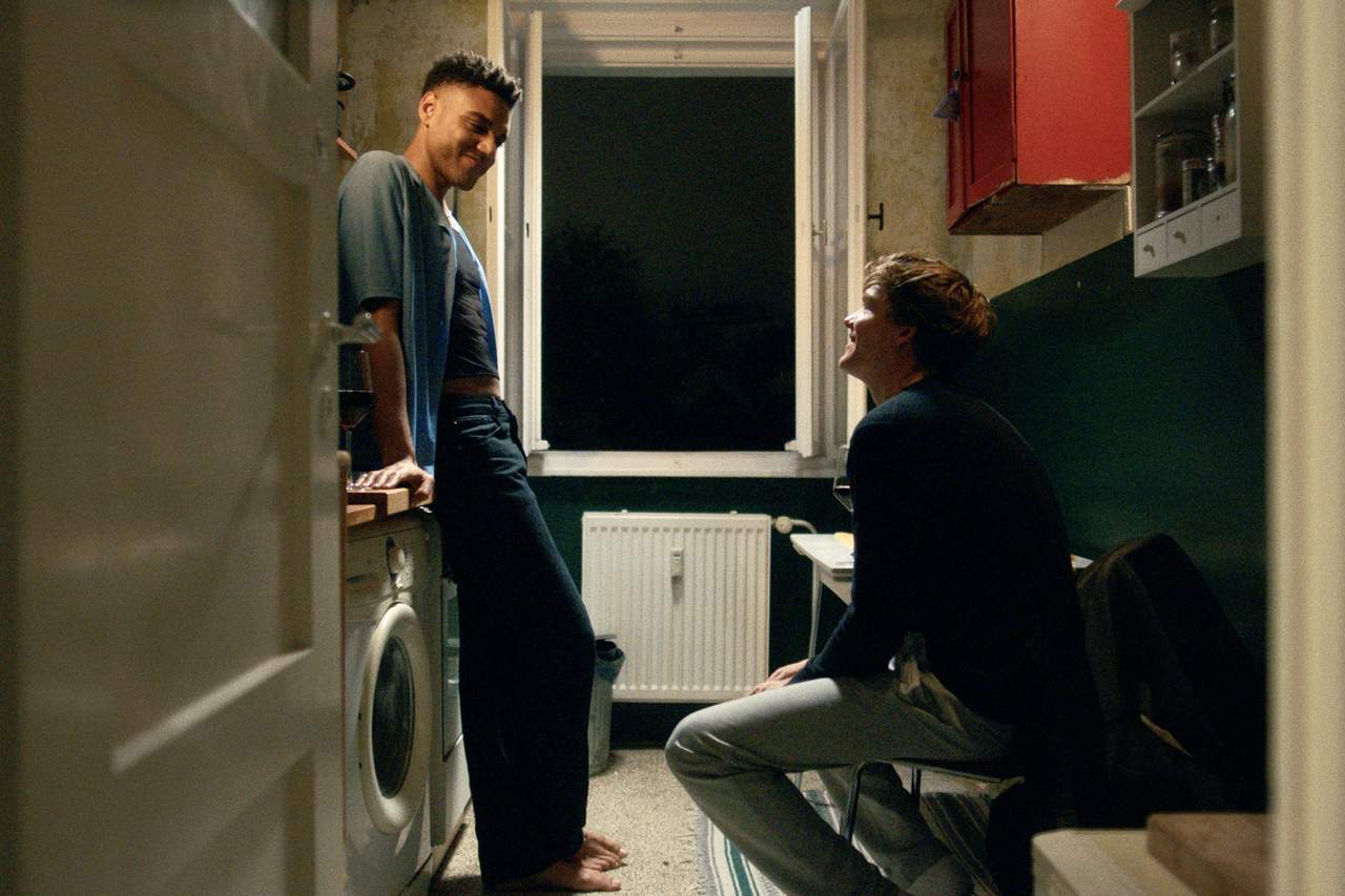 Malik (Lamin Leroy Gibba) and Phillip (Til Schindler) having a conversation in Malik's home