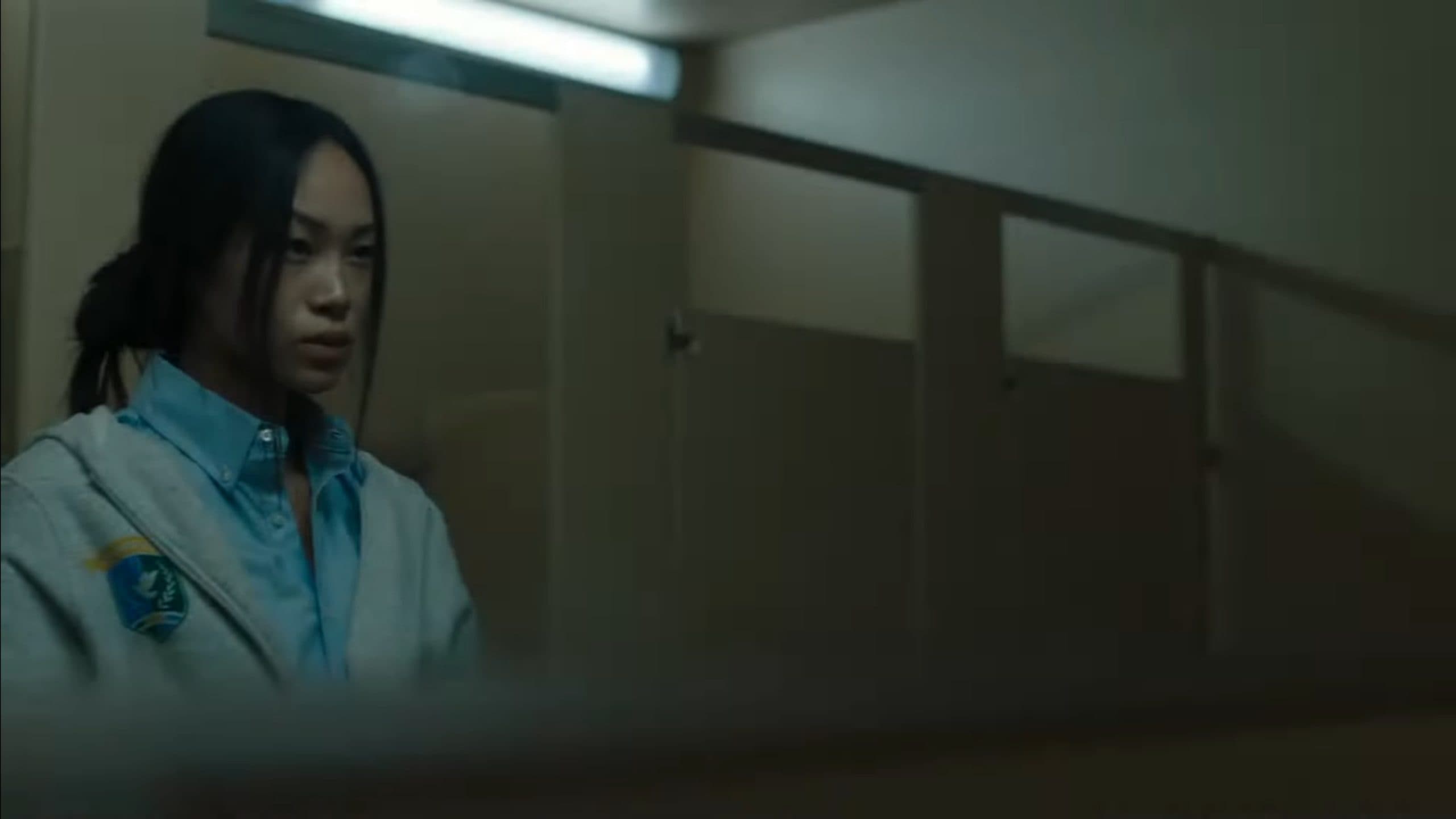 Jane (Chloe Yu) looking at Olivia in the girl's bathroom