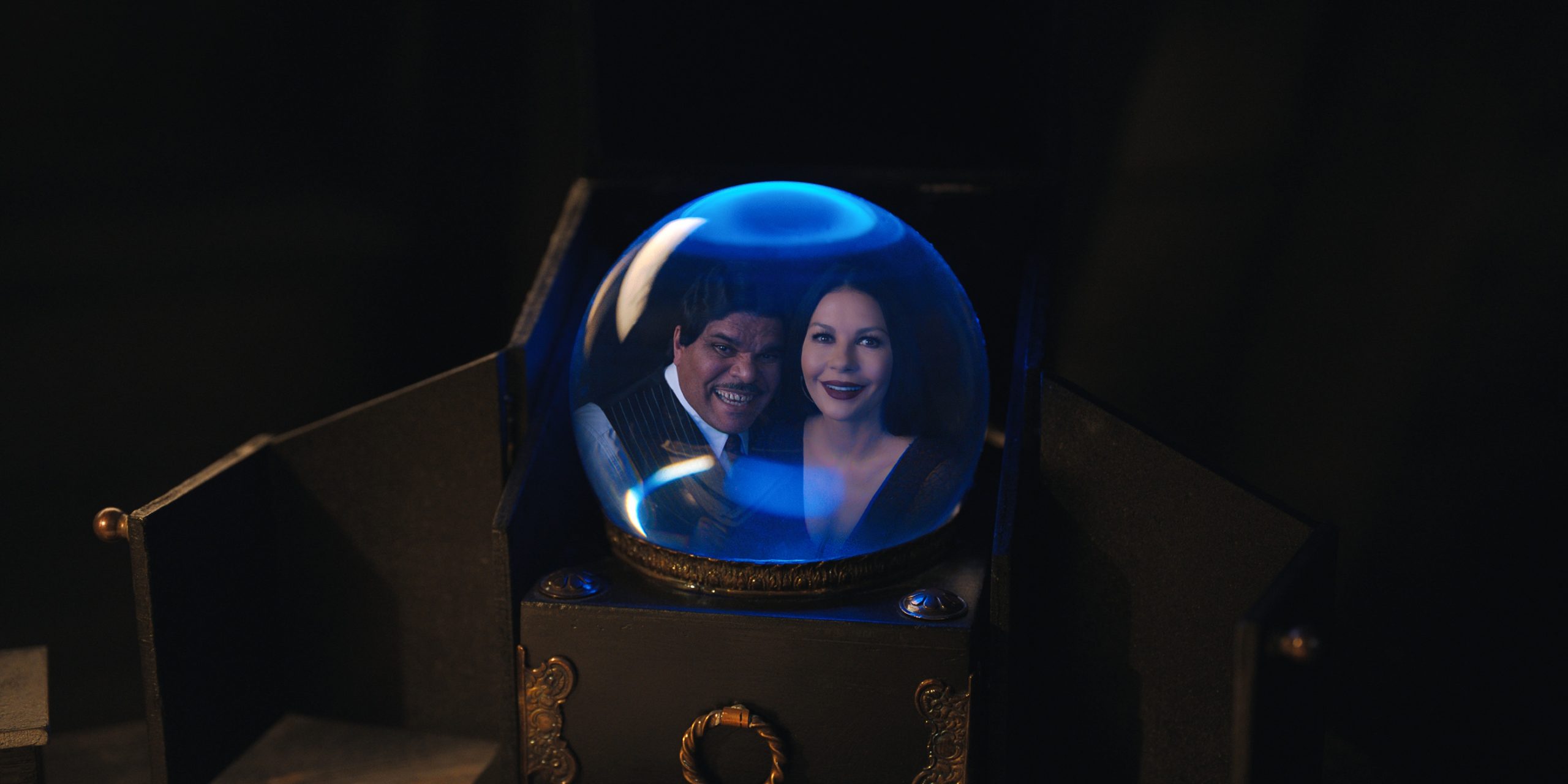 Gomez (Luis Guzman) and Morticia (Catherine Zeta-Jones) calling Wednesday via a crystal ball