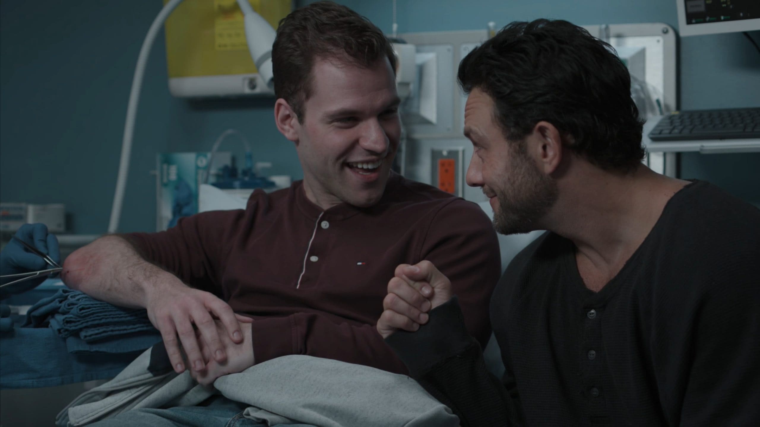 Ollie (Reggie Herold) smiling at his brother, as doctors examine him