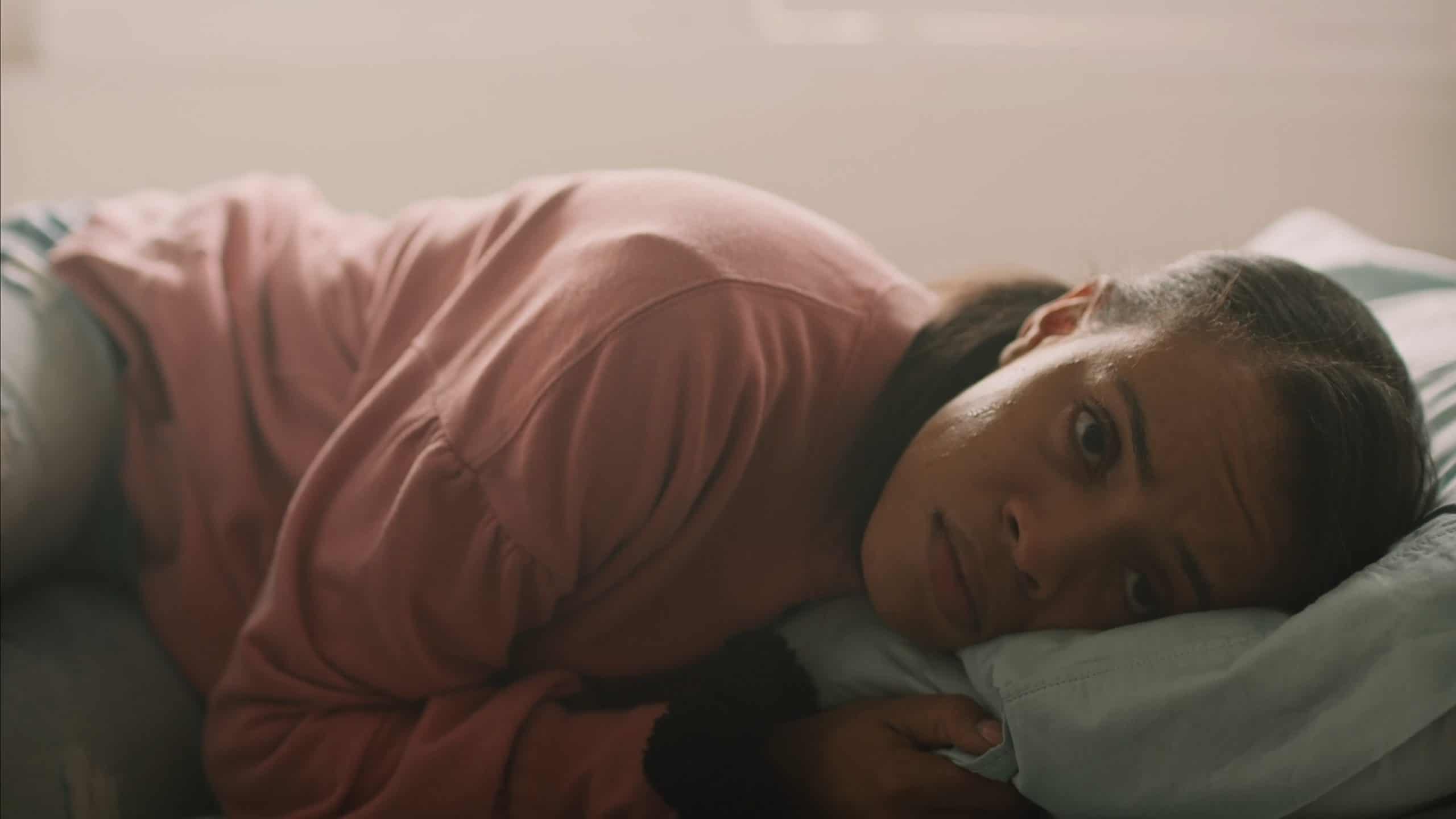 Angel (Efangeliz Medina) laying on her bed, starving