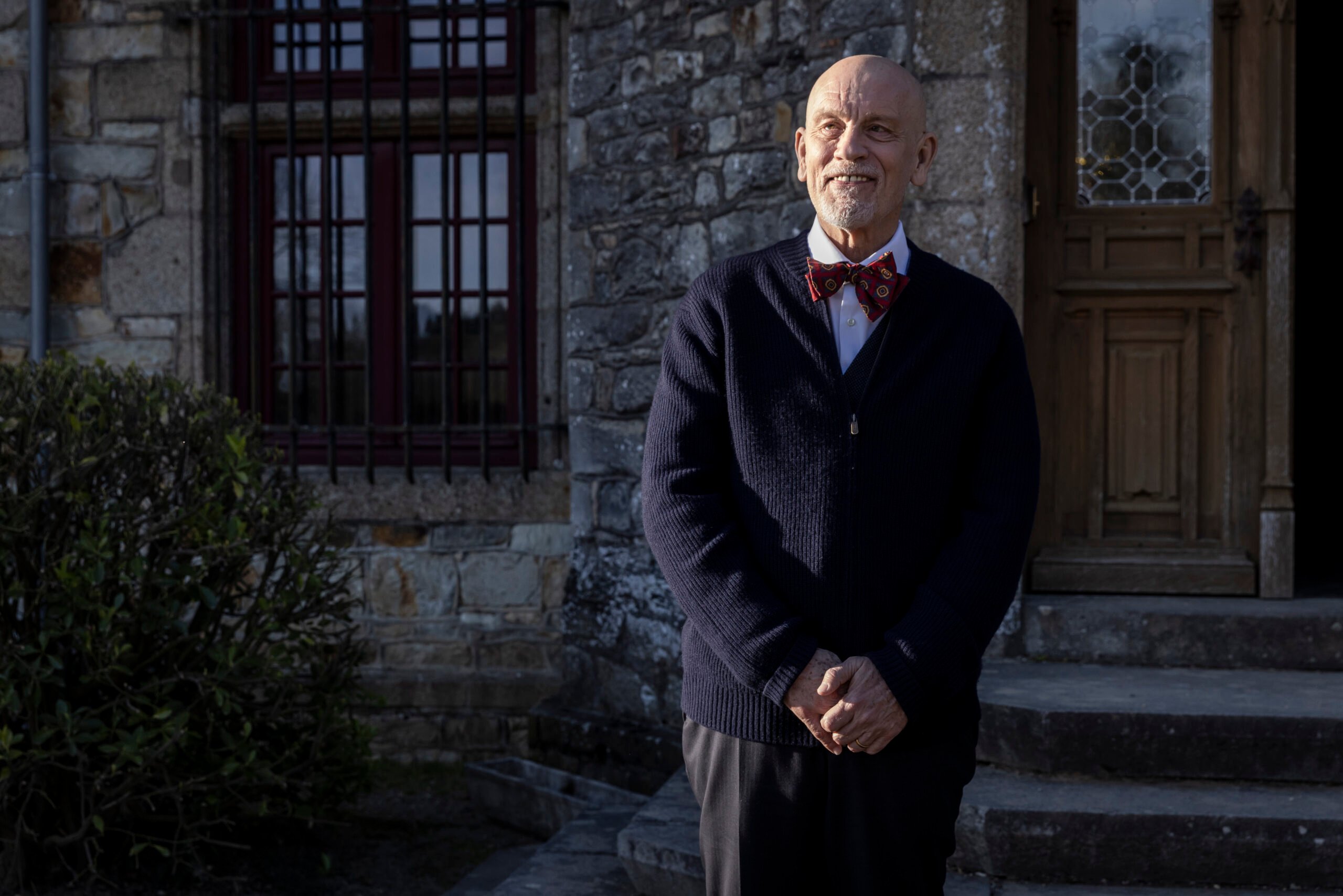 Andrew Blake (John Malkovich) standing in front of the Beauvillier estate – Mr. Blake At Your Service