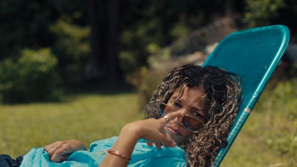 Bird (Alisha Wainwright) sitting in a chair outside, lowering her glasses to look at something - Bird In Hand (Source - Tribeca Film Festival Page) | Bird Alisha Wainwright Bird In Hand Source Tribeca Film Festival Page Bird (Alisha Wainwright) sitting in a chair outside, lowering her glasses to look at something - Bird In Hand (Source - Tribeca Film Festival Page)