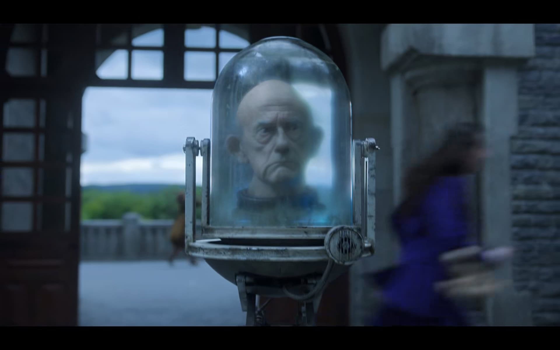 Dr. Orloff (Christopher Lloyd) moving through the courtyard - Wednesday Season 2 Episode 2
