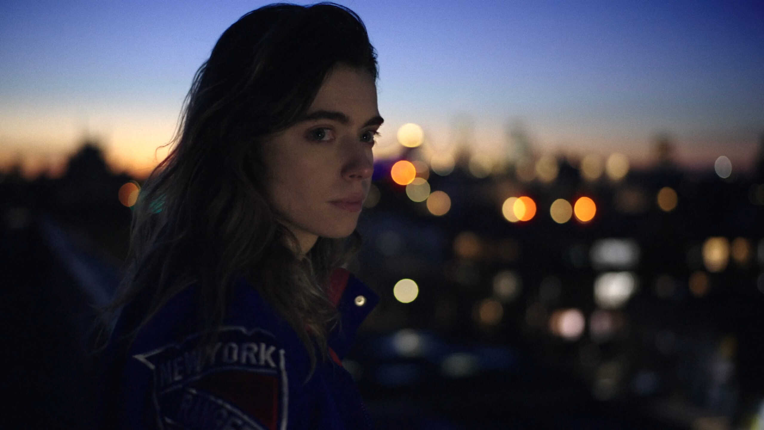 Kacey (Marta Piekarz) looking over at Anna, while they share a rooftop – Happy Place
